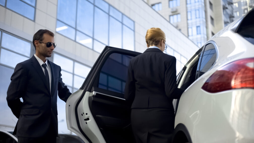 A person providing executive transport services and opening a vehicle door for a VIP