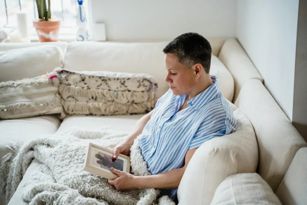 A woman sitting on a couch holding a picture as missing person private investigators search for this individual