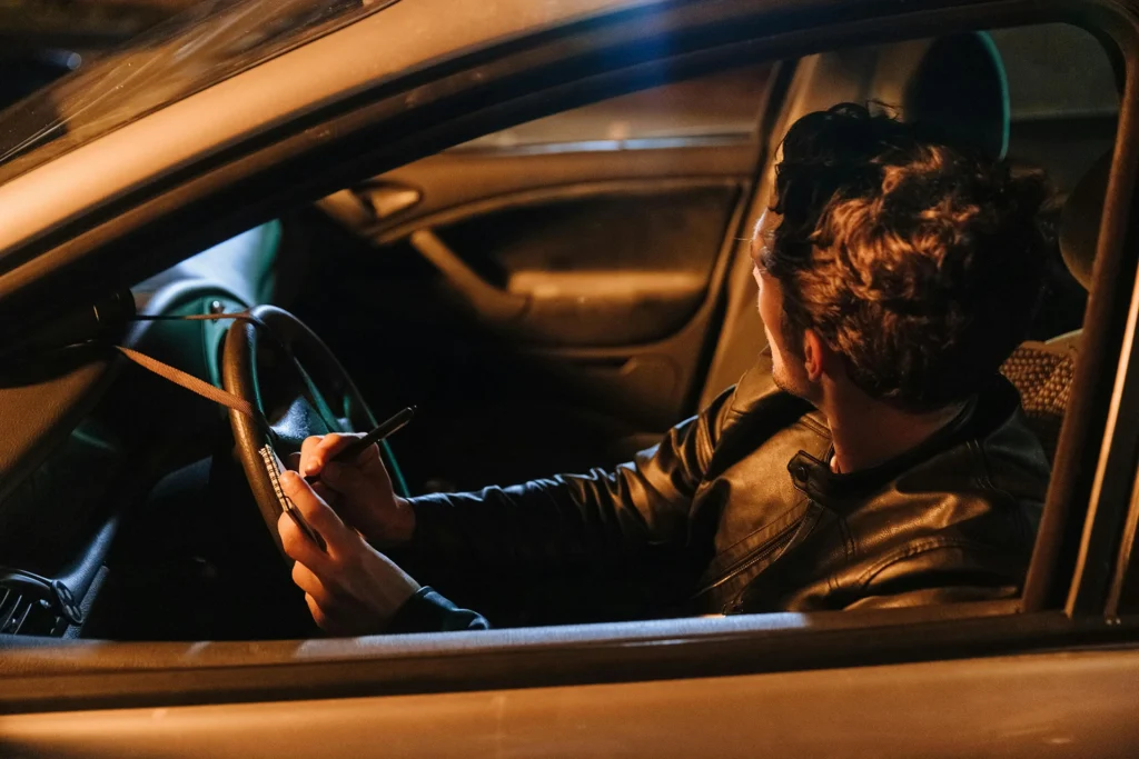 undercover-investigation A person in a car with a notepad conducting an undercover investigation